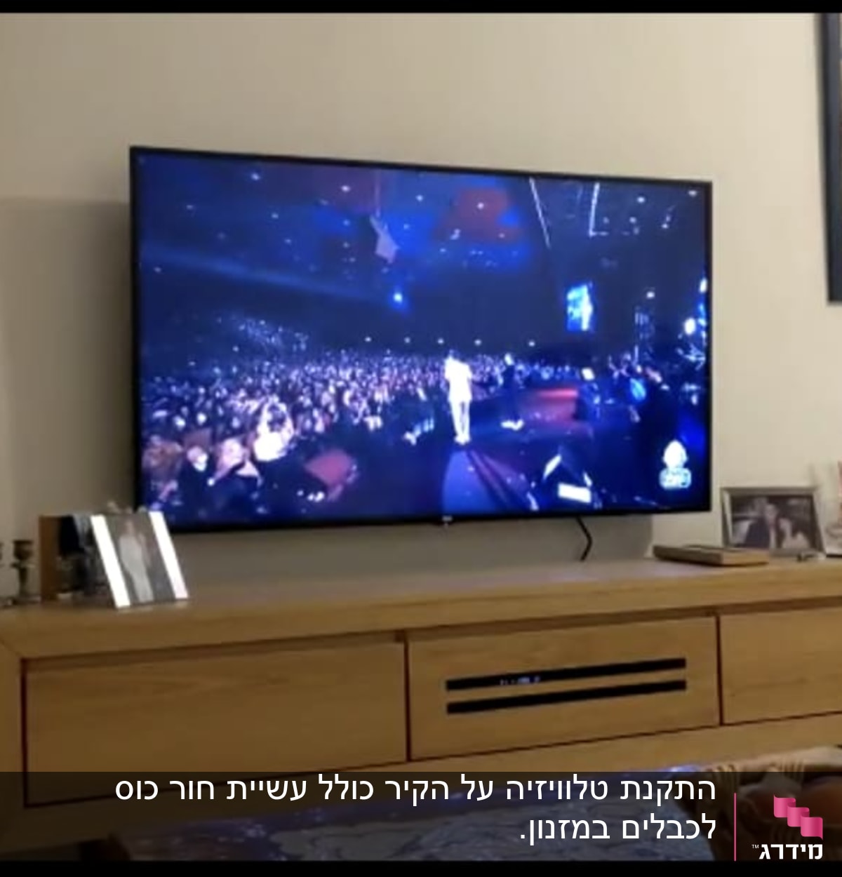 טלוויזיה תלויה על הקיר מעל שידה מעץ